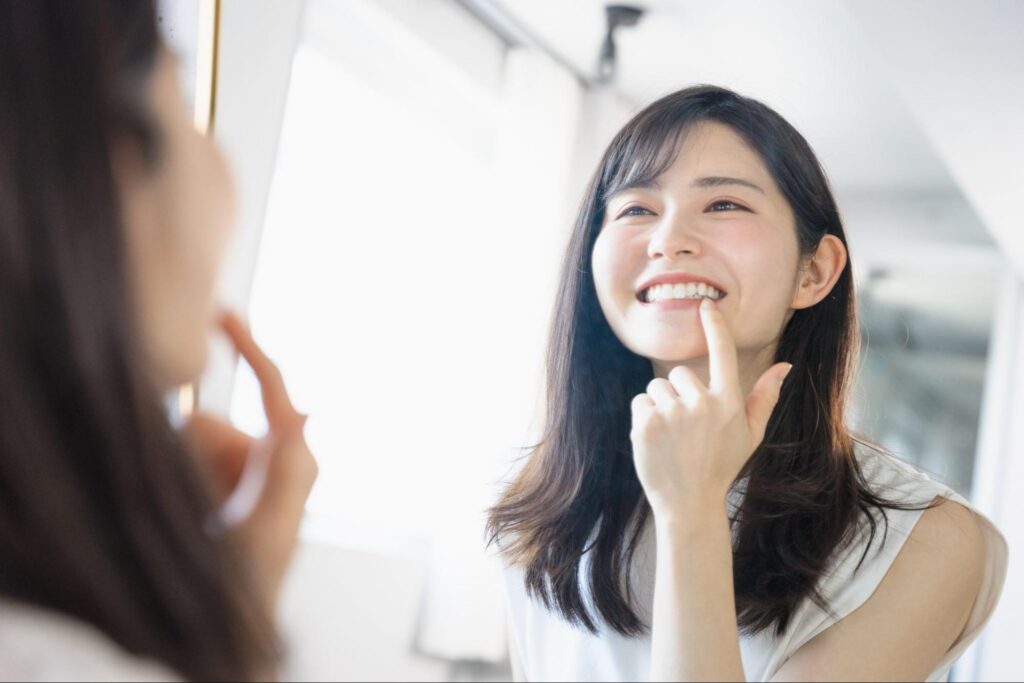 鏡で歯を見る女性