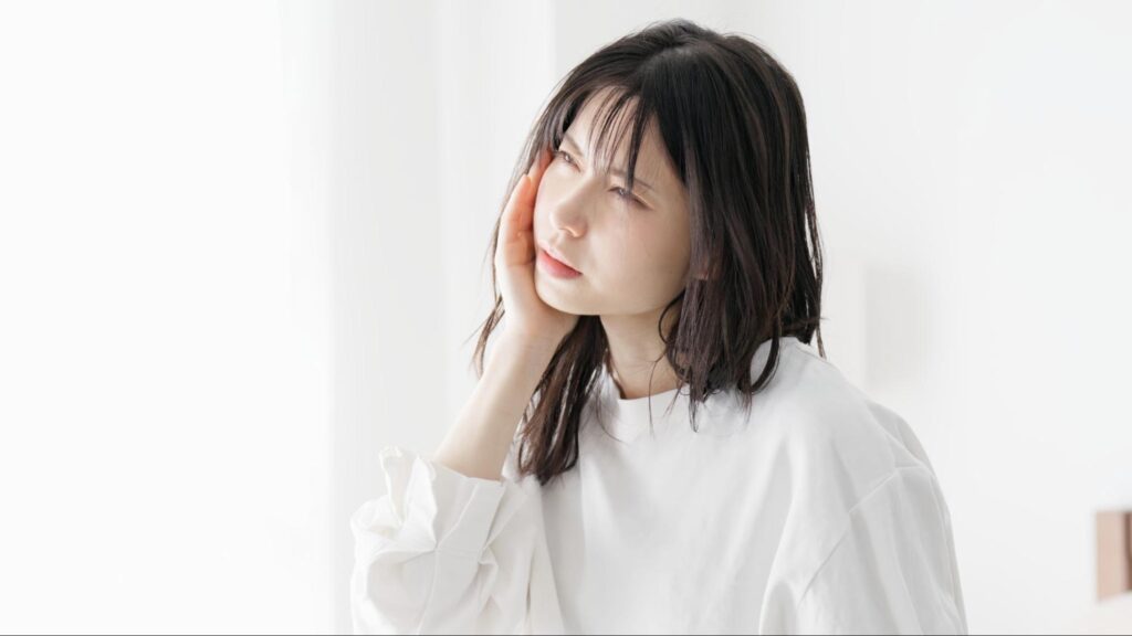頬に手を当てて考える女性