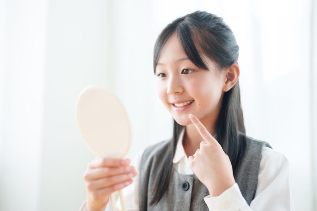 口元を鏡で見る若い女性