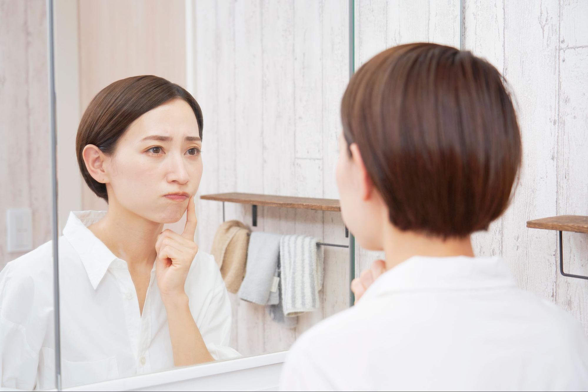 困った顔で鏡を見る女性