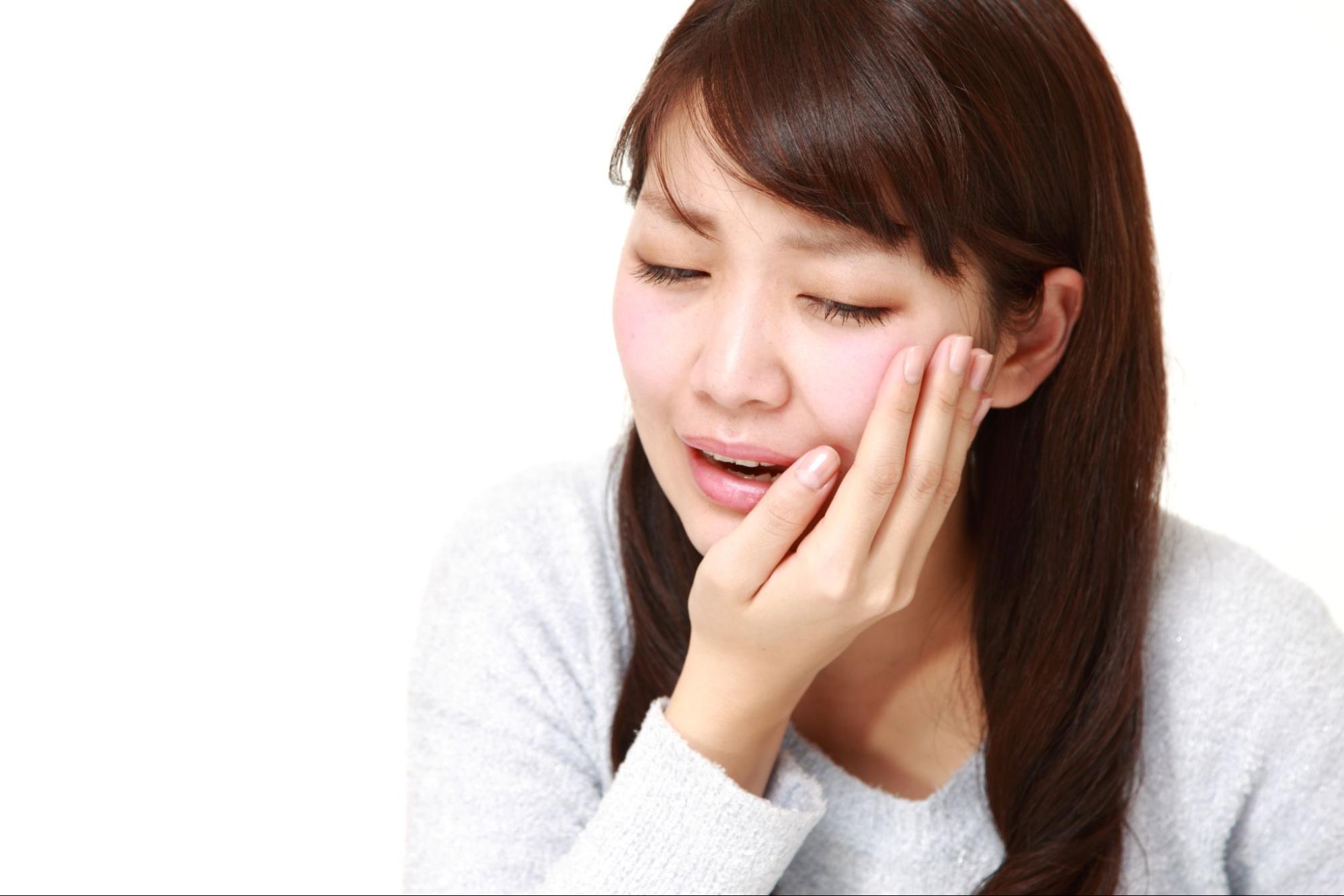 痛そうに頬を押さえる女性