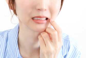 噛むと親知らずが痛み頬を抑える女性