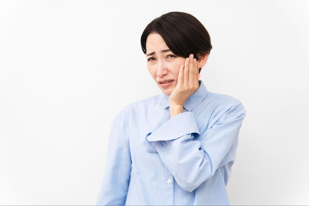 親知らずが痛み頬を抑える女性