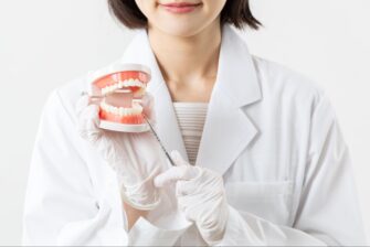 歯の模型を使って虫歯について説明する女性医師
