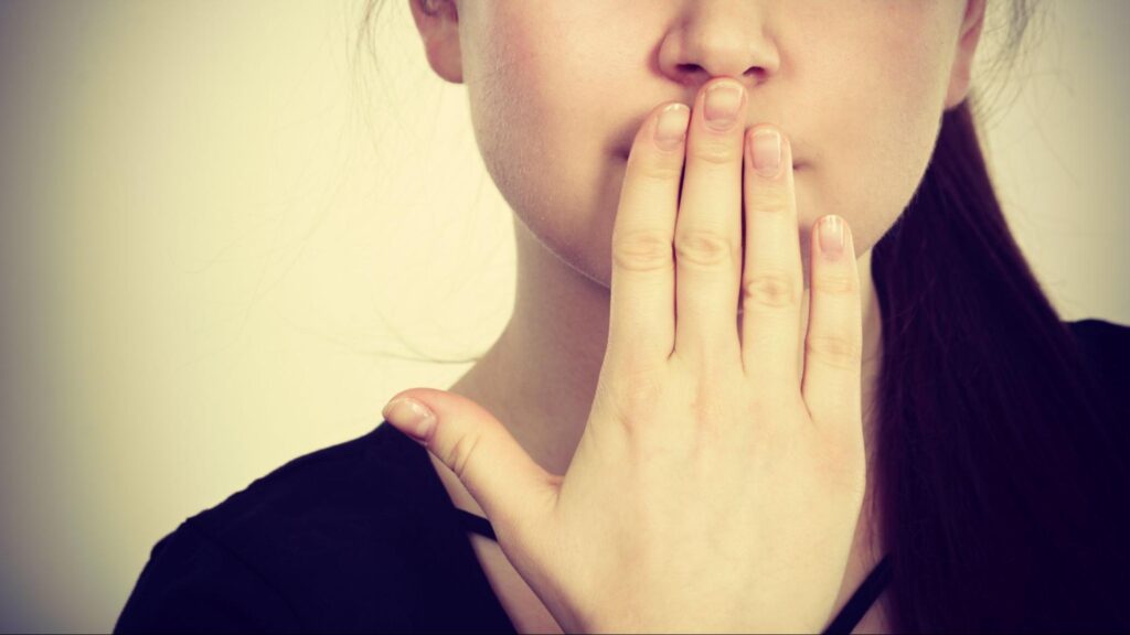 虫歯による口臭が気になり口元に手を当てる女性