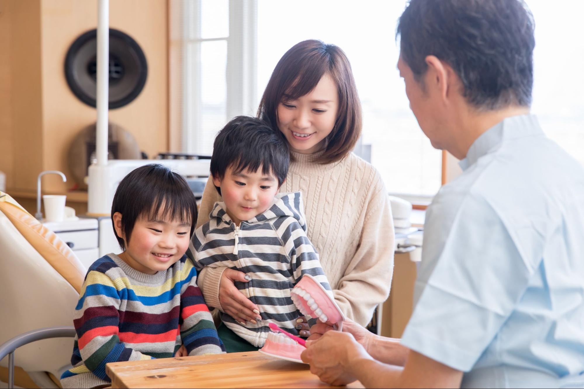 歯科医院で歯磨きの指導を受ける親子