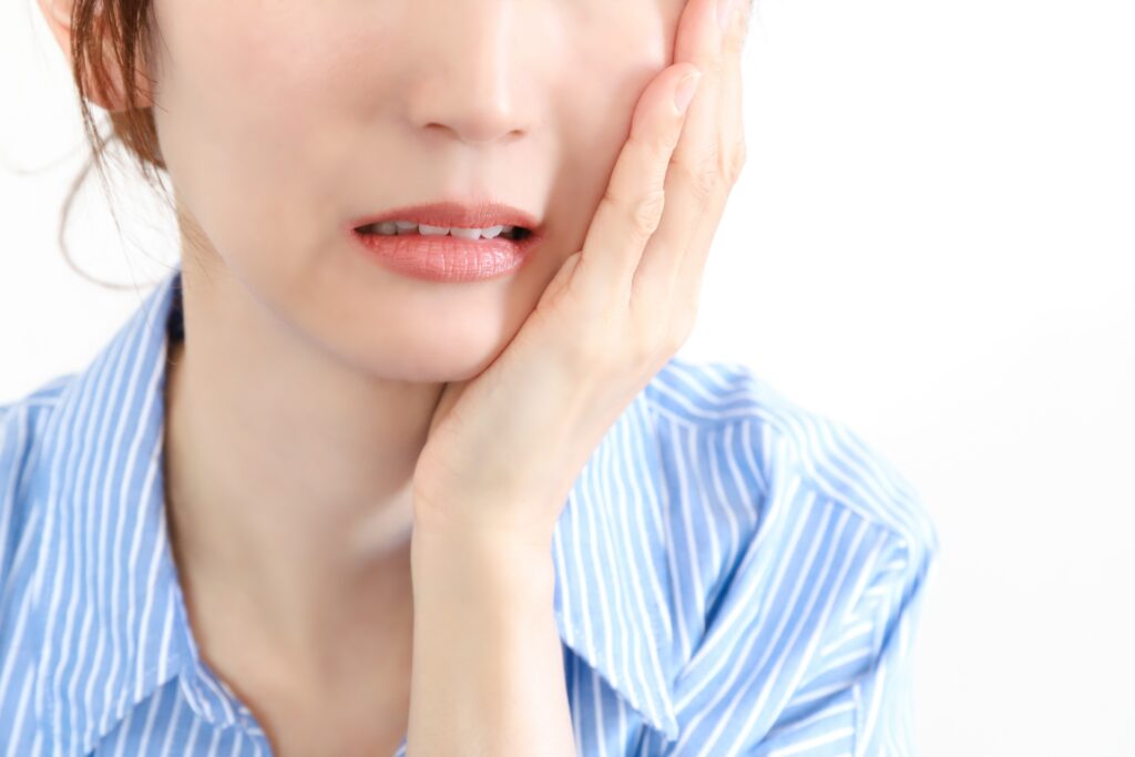 親知らずが痛み頬を抑える女性