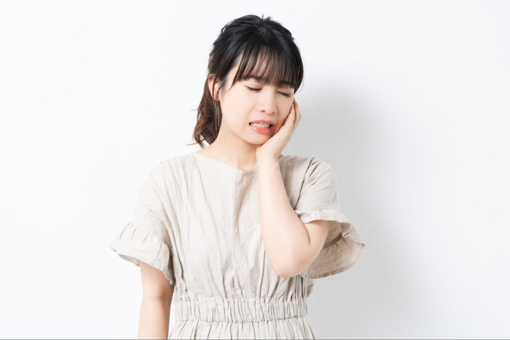 親知らずの痛みがピークで頬を抑え受診を検討する女性