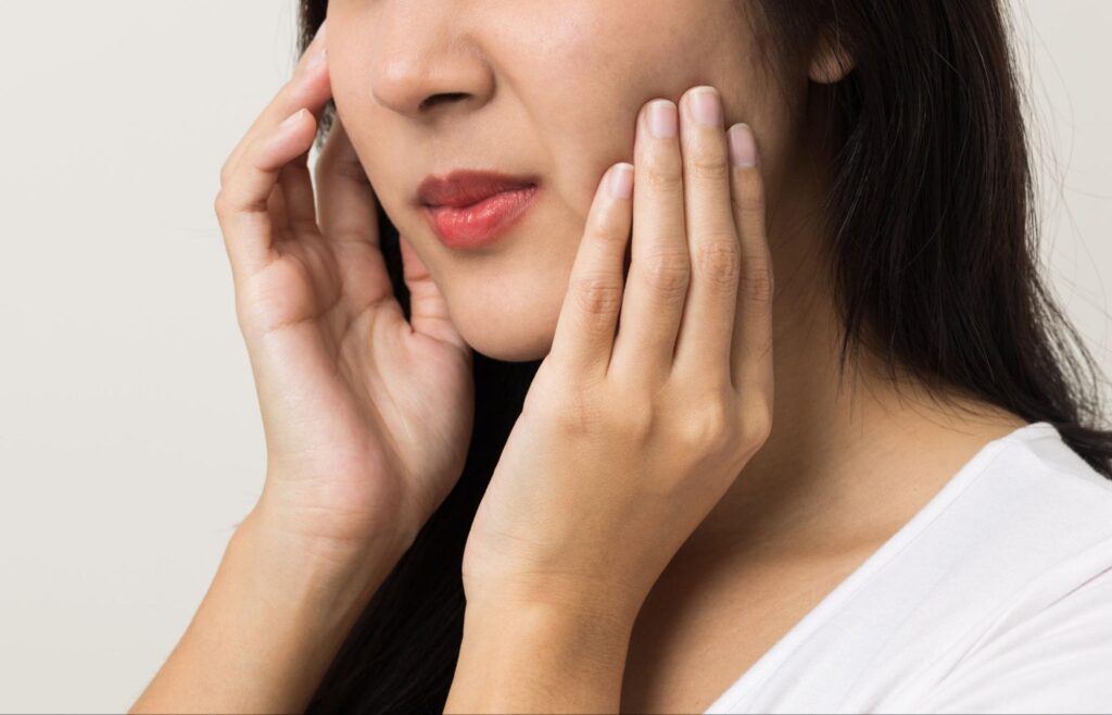 歯の痛みで頬を押さえる女性