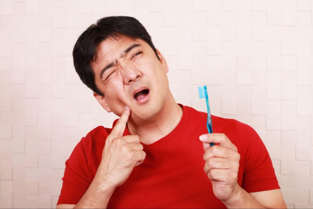 虫歯が多く歯磨き中に痛みを感じている男性