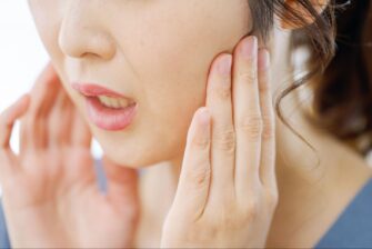 親知らずが痛み頬を抑える女性