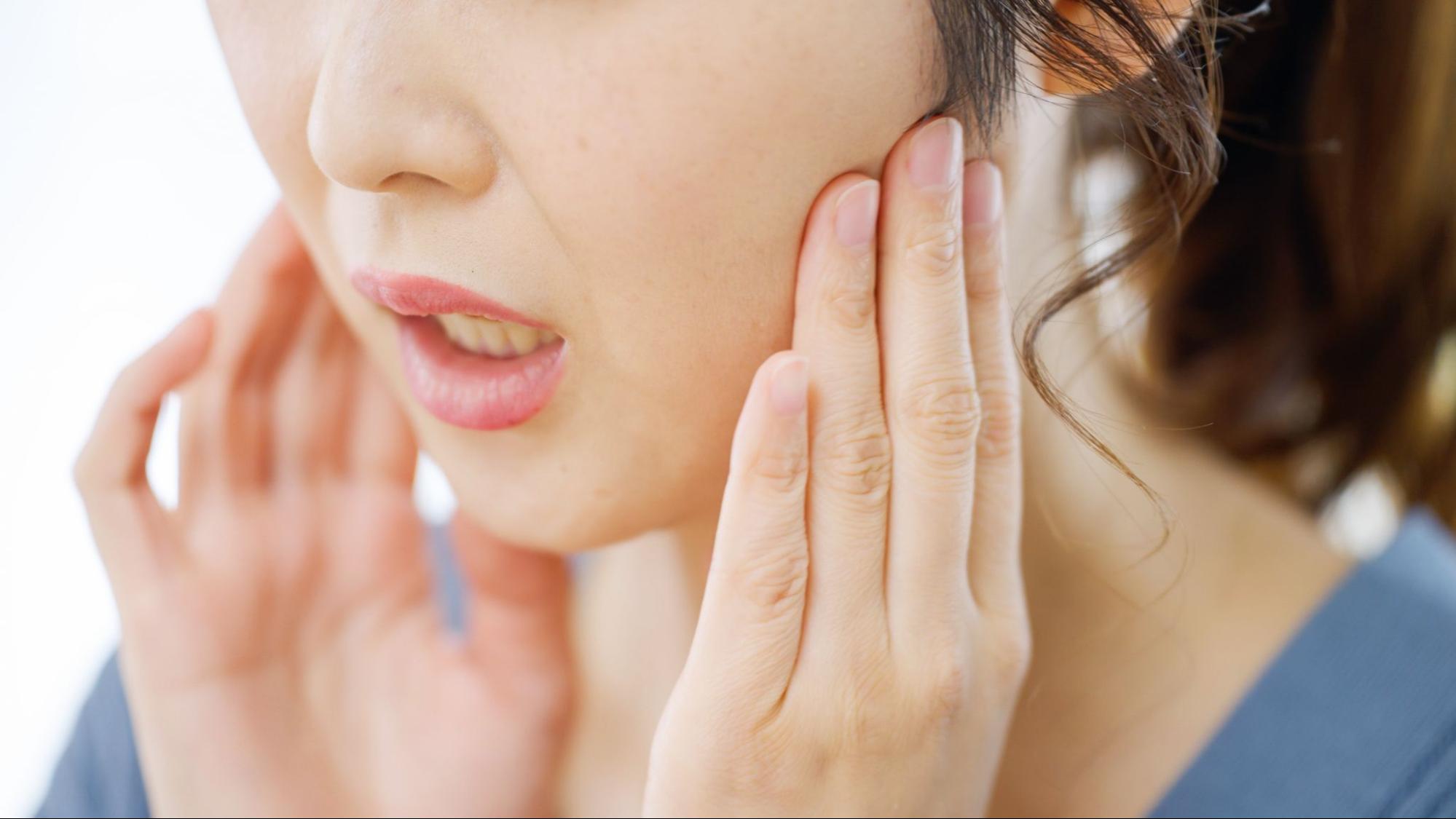 親知らずが痛み頬を抑える女性