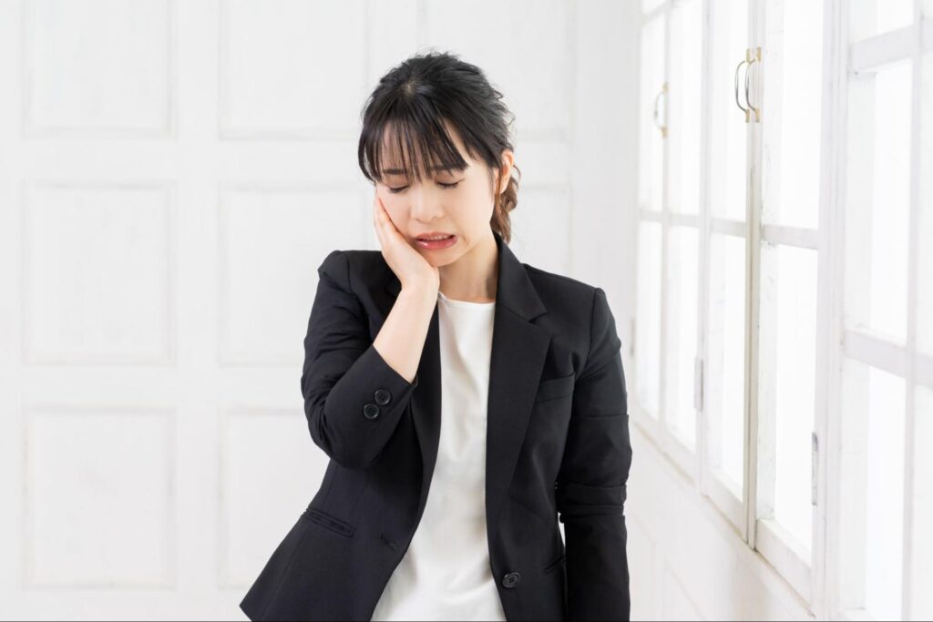 親知らずが痛み頬を抑える女性