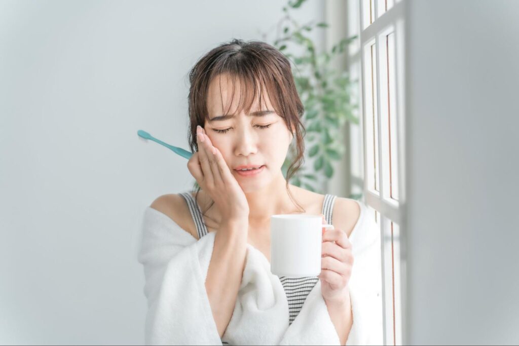 親知らずが痛み歯磨き中に頬を押さえる女性