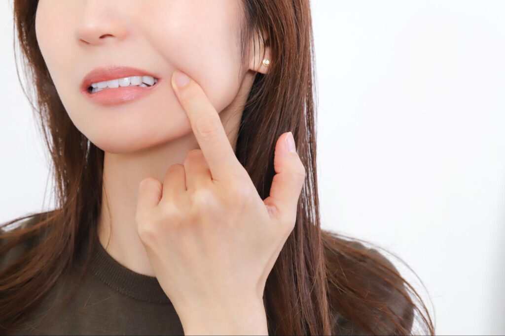 親知らずが痛み頬を抑える女性