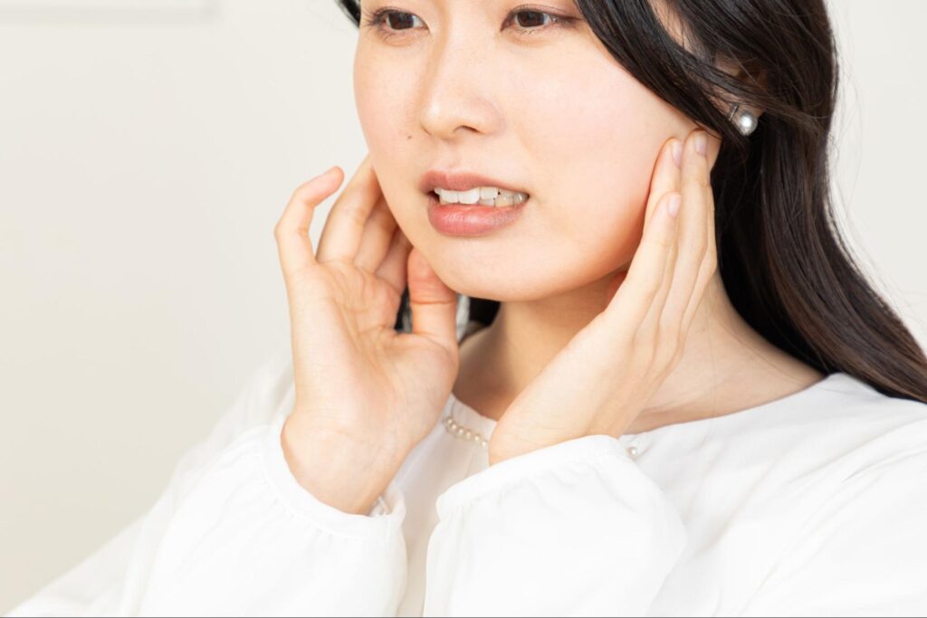 親知らずが痛み頬を抑える女性