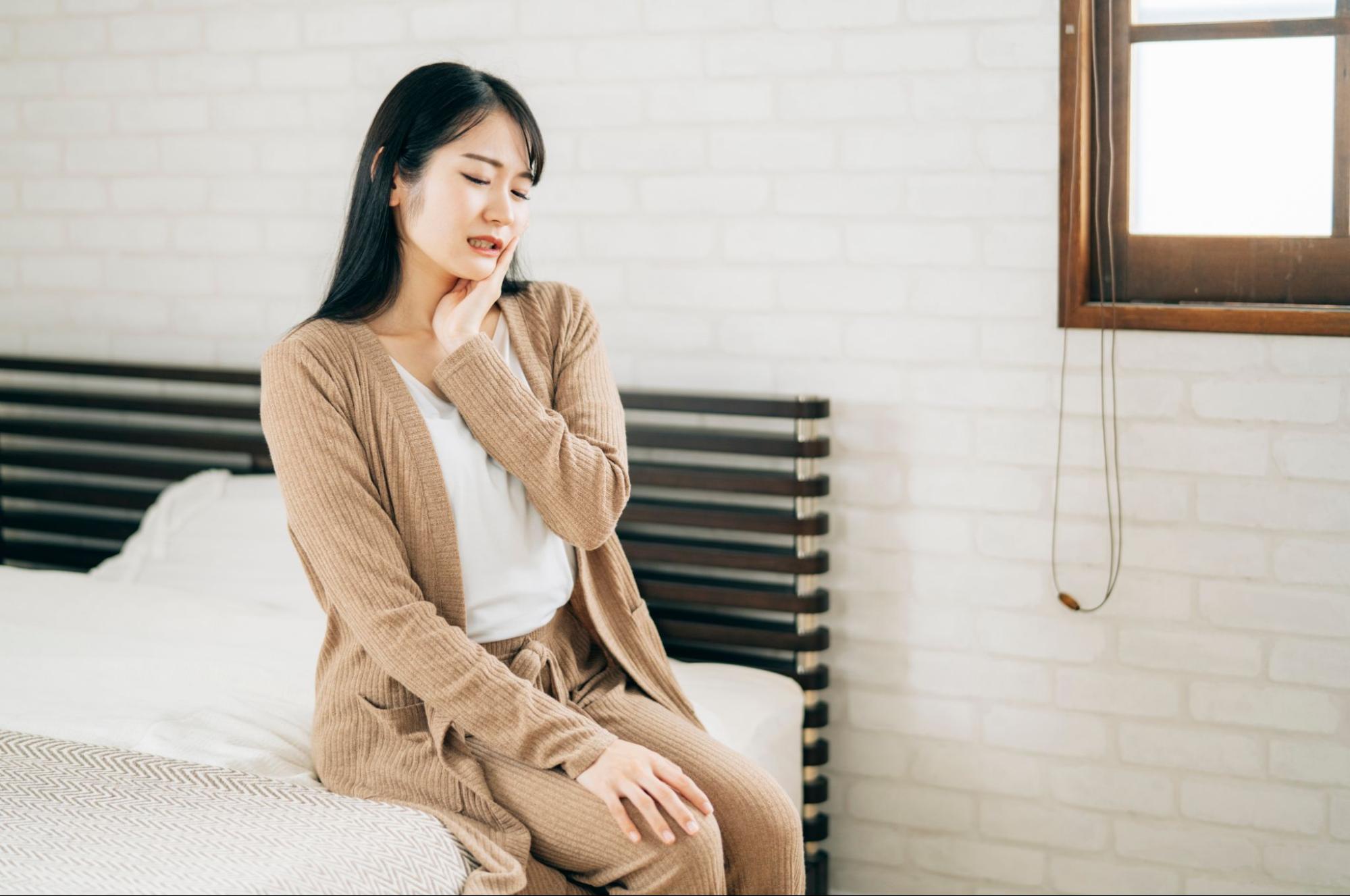 親知らずの痛みがピークで頬を抑える女性