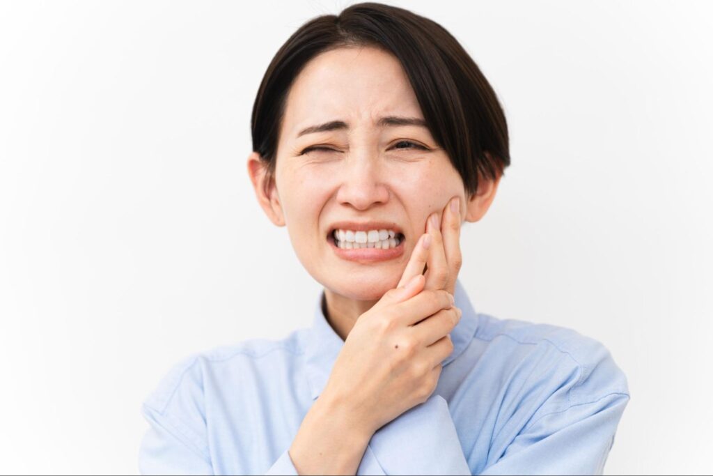親知らずが痛み頬を押さえる女性