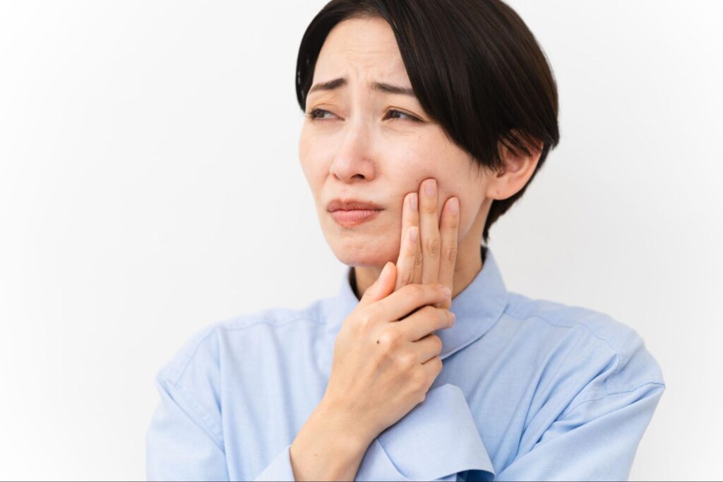 親知らずが痛み頬を押さえる女性