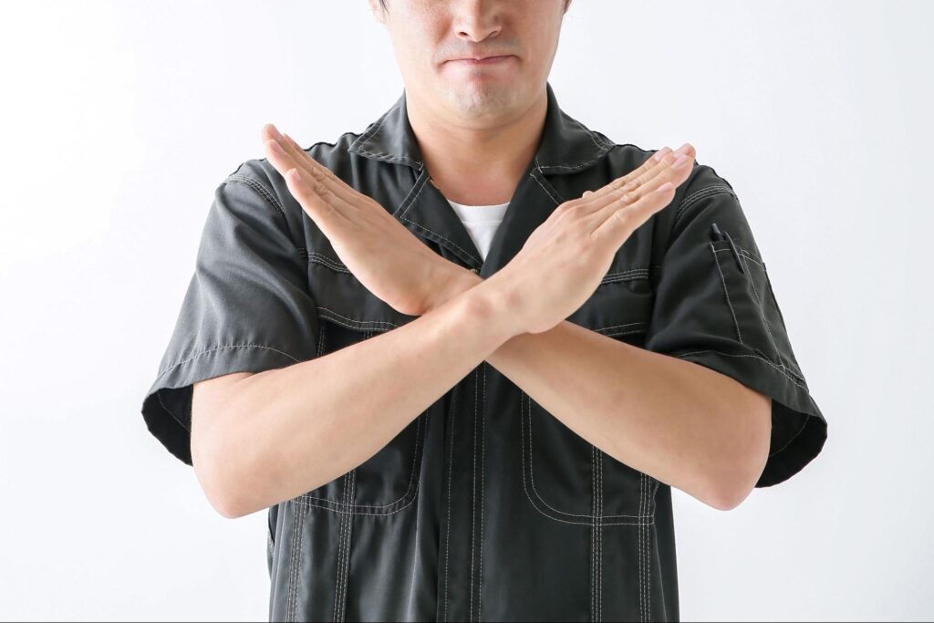 手でバツを作る男性