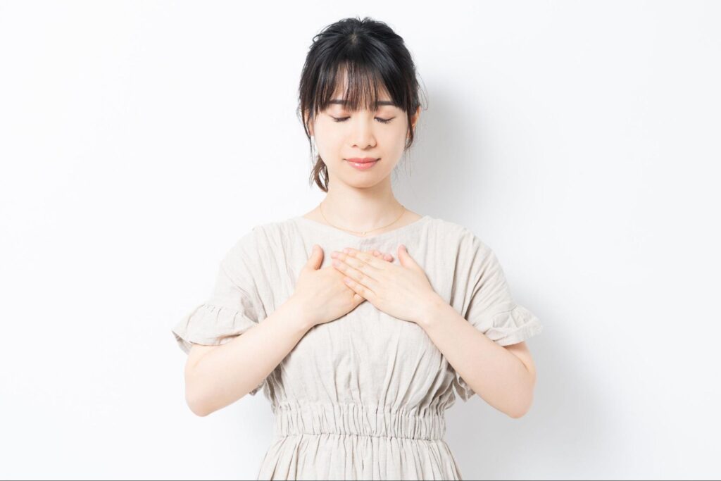 胸に両手を当てる女性