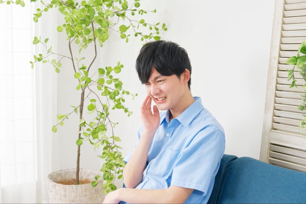 親知らずが痛み頬を抑える男性