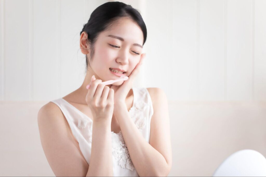 親知らずが痛み歯磨き中に頬を抑える女性