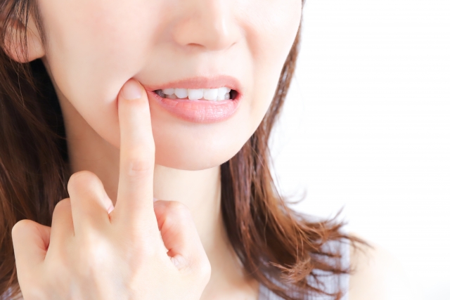 親知らずが痛み頬を押さえる女性
