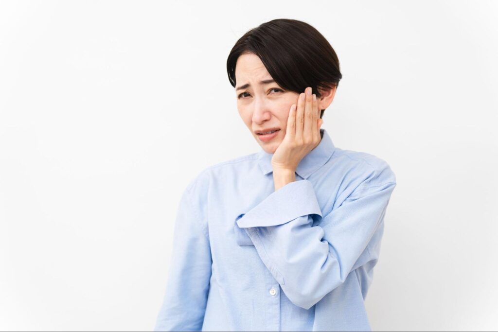 親知らずが痛み頬を抑える女性