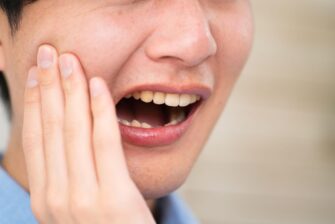 親知らずが痛み頬を押さえる男性